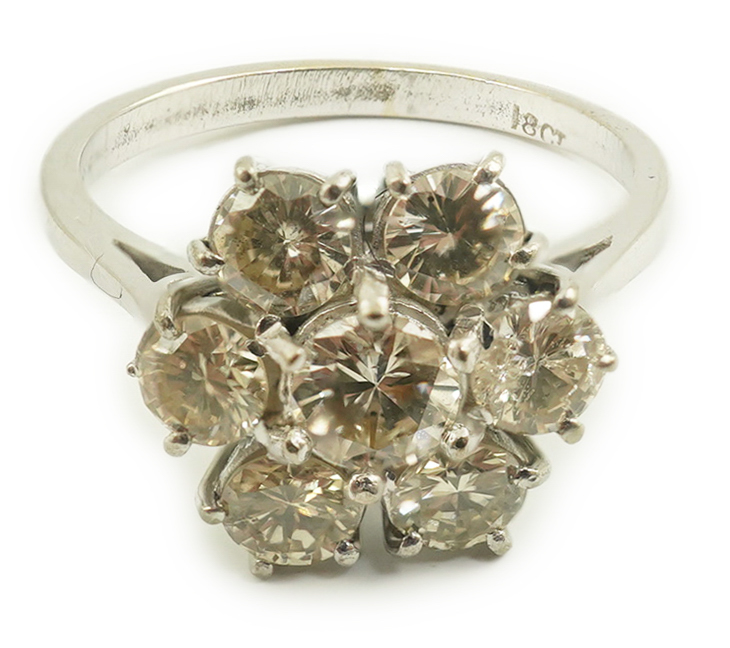 An 18ct white gold and seven stone diamond set flower head cluster ring